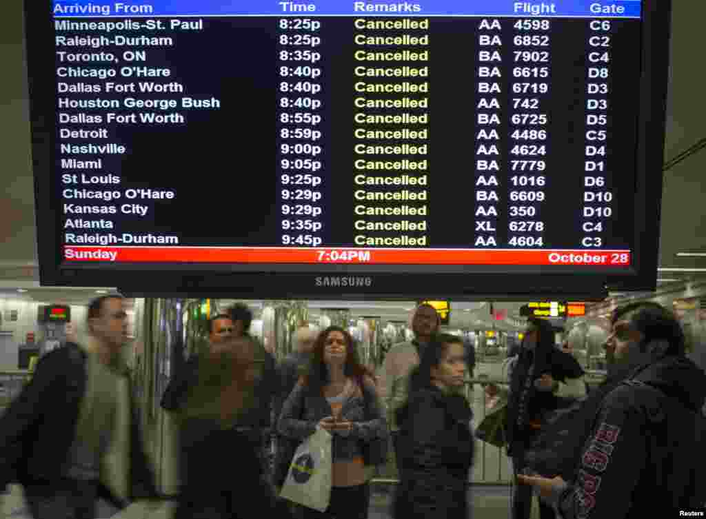 Travelers surround a flight monitor showing cancelled flights at LaGuardia airport in New York October 28, 2012.