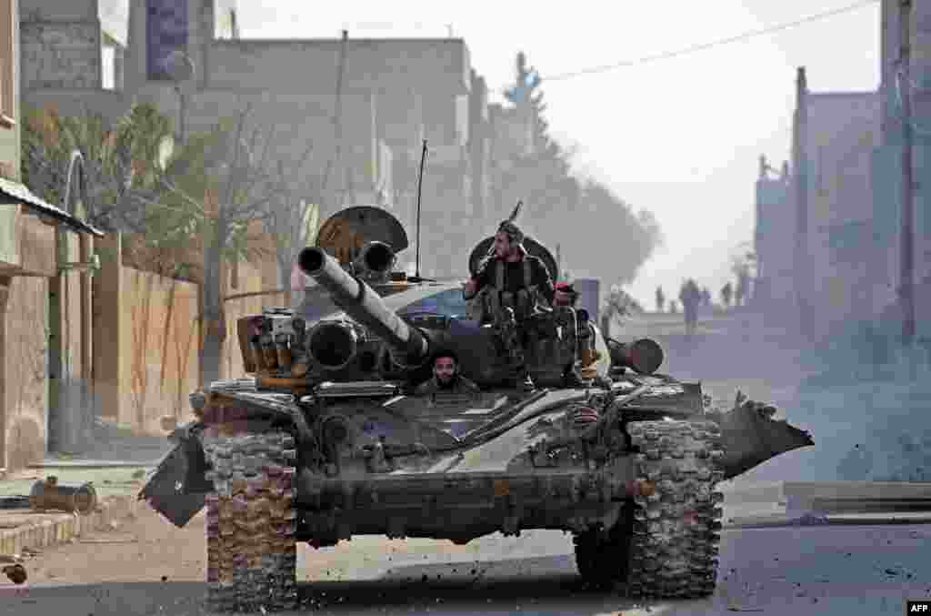 Turkey-backed Syrian fighters drive a tank through the town of Saraqib in the eastern part of Idlib Province in northwestern Syria.