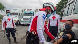 Los trabajadores de la Cruz Roja Internacional controlan la presión y la temperatura de los camioneros durante un bloqueo en la frontera de Peñas Blancas entre Nicaragua y Costa Rica, en Rivas, Nicaragua, el 28 de mayo de 2020. 