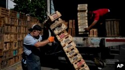 ARCHIVO - Trabajadores cargan cajas en un camión mientras van y vienen del mercado principal para cargar productos para vender en Buenos Aires, Argentina, el lunes 11 de diciembre de 2023.