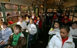 FILE - A multi-racial group of students sit next to each other on the actual bus where Rosa Parks, a black woman, refused to give up her seat to a white man in 1955 in Alabama, during their visit to Henry Ford Museum in Michigan, Oct. 25, 2005.
