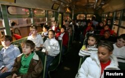 FILE - A multi-racial group of students sit next to each other on the actual bus where Rosa Parks, a black woman, refused to give up her seat to a white man in 1955 in Alabama, during their visit to Henry Ford Museum in Michigan, Oct. 25, 2005.