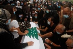 Relatives of Lebanese army lieutenant Ayman Noureddine, who was killed by Tuesday's explosion that hit the seaport of Beirut, mourn over his coffin during his funeral procession, in Numeiriyeh village, south Lebanon, Aug. 7, 2020.
