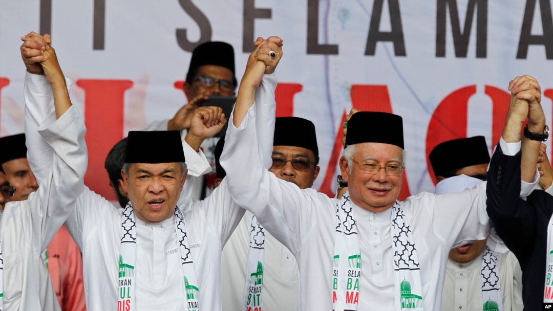 Perdana Menteri Malaysia Najib Razak (kanan) menggandeng tangan Wakil Perdana Menteri Zahid Hamidi dalam sebuah pawai di Masjid Putra, di Putrajaya, Malaysia, Jumat, 22 Desember 2017.
