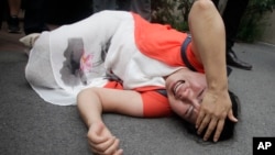 Fan Lili, the wife of imprisoned activist Gou Hongguo, lies on the ground in tears following an interaction with a plainclothed police officer outside the Tianjin No. 2 Intermediate People's Court in Tianjin, China on Aug. 1, 2016. 