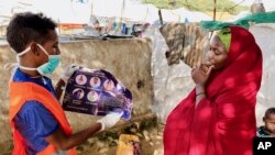 Seorang perempuan Somalia diberi tahu bagaimana melindungi dirinya dari virus corona, di kamp IDP Weydow di Mogadishu, Somalia. (Hamza Osman/International Organization for Migration via AP)