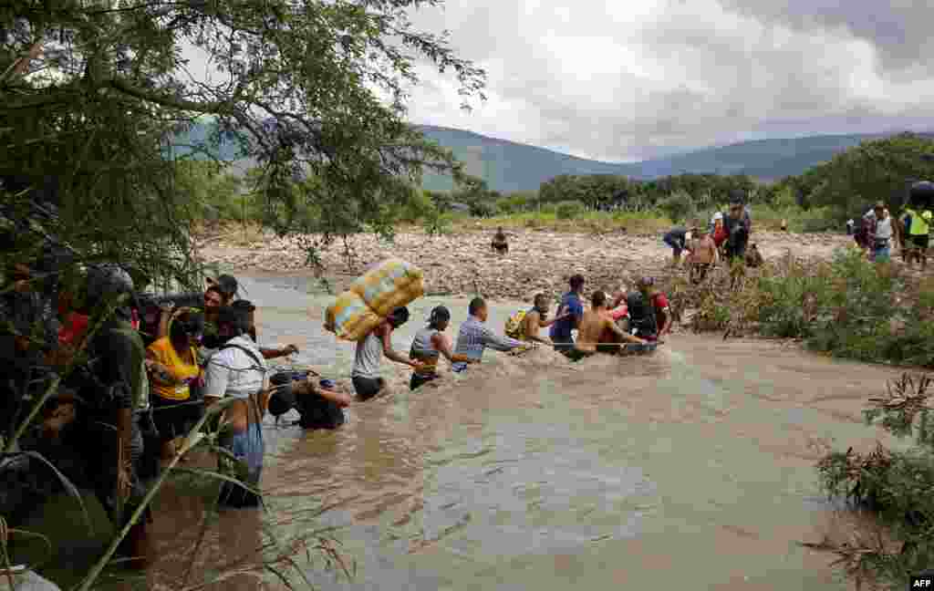 Para migran menggunakan tali untuk menyeberangi Sungai Tachira, perbatasan antara Kolombia dan Venezuela, karena perbatasan resmi ditutup untuk menghindari perebakan pandemi COVID-19 di Cucuta, Kolombia, 19 November 2020. (Foto: AFP)