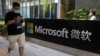 A man looks at his smartphone as he walks by the Microsoft office in Beijing on August 7, 2020. The Biden administration on Monday, July 19, 2021, blamed China for a hack of Microsoft Exchange email server software that compromised tens of thousands of computers worldwide.