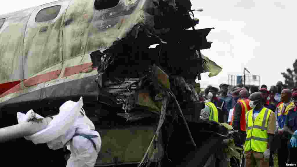 Rescue officials stand near the wreckage of a plane at the site of its crash near the Lagos airport.