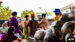 This picture taken on June 7, 2021 shows people queueing to receive food donations in a camp for displaced people in Namkham township in Shan state in eastern Myanmar.