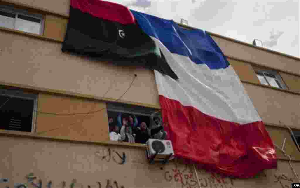 Libyan people celebrate next to a French flag in the main square of Benghazi, easterm Libya, Friday, March 18, 2011. The U.N. Security Council voted Thursday to impose a no-fly zone over Libya and authorize "all necessary measures" to protect civilians fr