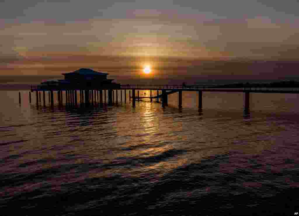طلوع خورشید بر فراز یک اسکله در دریای بالتیک در تیمندورفر اشتراند، در شمال آلمان
