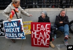 FILE - Brexit supporters display their signs in front of Parliament in London, Oct. 23, 2019.