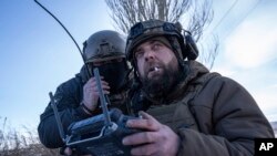 A Ukrainian serviceman aka Zakhar, right and commander of a unit aka Kurt, look on a screen of a drone remote control during fighting, at the frontline in Donetsk region, Ukraine, Feb. 13, 2023. 