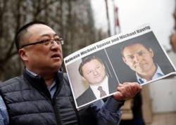 FILE - A protester holds a sign calling for China to release Canadian detainees Michael Spavor and Michael Kovrig outside a court hearing for Huawei executive Meng Wanzhou in Vancouver, March 6, 2019.