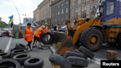 FILE - Municipal workers remove tires as they dismantle barricades set up during the protests that toppled Moscow-backed president Viktor Yanukovych in central Kyiv, July 1, 2014. 