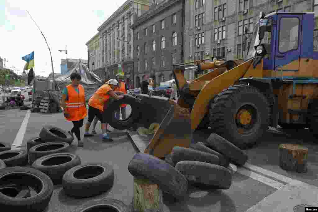 Municipal workers remove tires as they dismantle barricades set up during the protests that toppled Moscow-backed president Viktor Yanukovych in central Kyiv, July 1, 2014. 