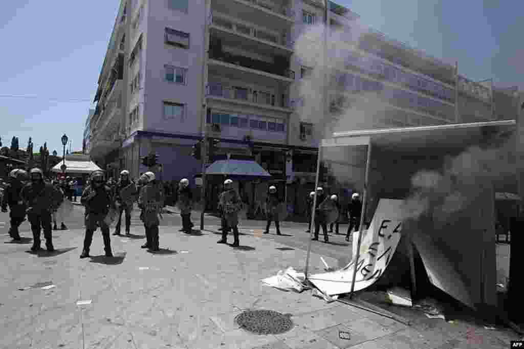 Riot police stand next to a burning election kiosk of an independent right-wing candidate by protesters during a May Day protest in Athens, May 1, 2012. (AP Photo)