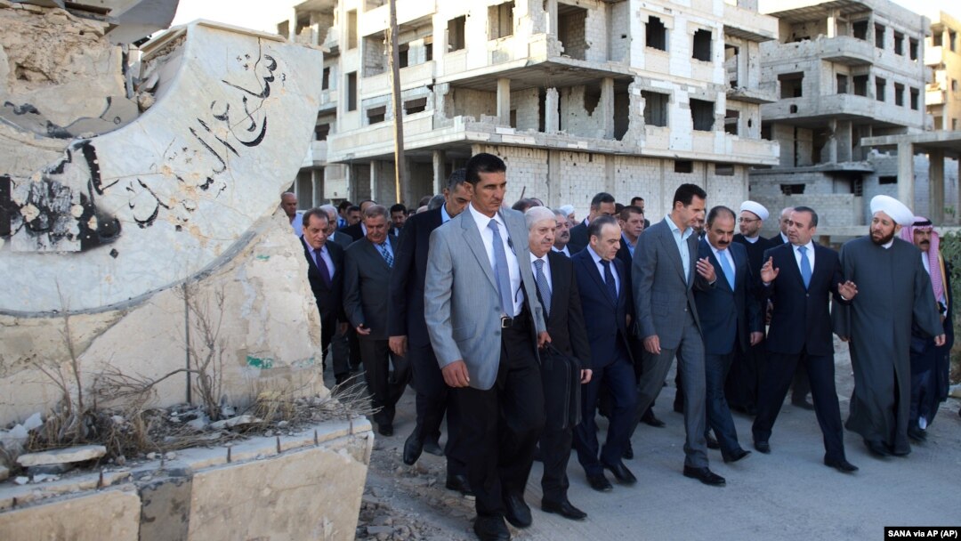 Foto divulgada por la agencia estatal de noticias siria, SANA, del presidente Bashar al Assad, centro, en los suburbios de Daraya, Damasco.