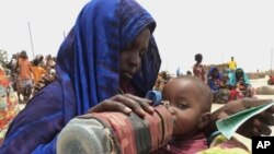 A mother quenches her malnourished child's thirst while waiting for food handouts at a health center in Ethiopia. File.