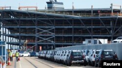 Cars readied for export are parked next to a vehicle storage facility on the dockside at the ABP port in Southampton, Britain, Aug. 16, 2017. 