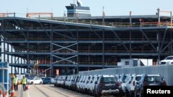 Cars readied for export are parked next to a vehicle storage facility on the dockside at the ABP port in Southampton, Britain, Aug. 16, 2017. 