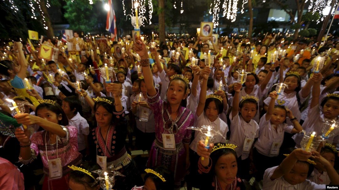 Warga Thailand memegang lilin dan foto Raja Thailand Bhumibol Adulyadej di rumah sakit Siriraj, di mana sekelompok orang berkumpul untuk merayakan ulang tahunnya yang ke-88, di Bangkok, Thailand, 5 Desember 2015.