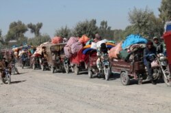 Afghan families leave their houses after fighting between the Afghan military and Taliban insurgents in Helmand province, southern of Afghanistan, Oct. 13, 2020.