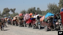 FILE - Afghan families leave their houses after fighting between the Afghan military and Taliban insurgents in Helmand province, southern Afghanistan, Oct. 13, 2020.