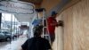 Men work boarding up a window as Francine approaches the U.S. Gulf Coast, in Morgan City, Louisiana, Sept. 10, 2024. 