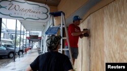 Men work boarding up a window as Francine approaches the U.S. Gulf Coast, in Morgan City, Louisiana, Sept. 10, 2024. 