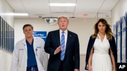 El presidente Donald Trump, en el centro, acompañado por la primera dama Melania Trump, a la derecha, y el Dr. Igor Nichiporenko, a la izquierda, hablan con los periodistas tras su visita al personal médico de Broward Health North en Pompano Beach, Florida, el 16 de febrero de 2018.