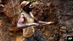 FILE - One of few remaining miners digs out soil which will later be filtered for traces of cassiterite, the major ore of tin, at Nyabibwe mine, in eastern Congo, Aug. 7, 2012.