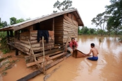 FILE - Kongvilay Inthavong and his wife, Thongla, clean up their house as the floodwaters start to recede in Sanamxay district, Attapeu province, Laos, July 26, 2018.