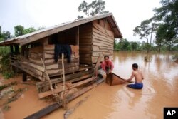 FILE - Kongvilay Inthavong and his wife, Thongla, clean up their house as the floodwaters start to recede in Sanamxay district, Attapeu province, Laos, July 26, 2018.