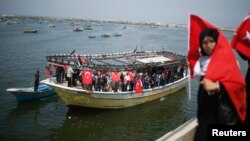 A Palestinian woman holds a Turkish flag as activists ride a boat during a rally ahead of the 4th anniversary of the Mavi Marmara Gaza flotilla incident, at the seaport of Gaza City, May 29, 2014.