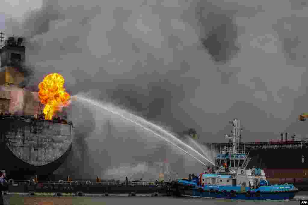 Fire fighters onboard a vessel extinguish a fire on a tanker ship docked in Belawan, Indonesia.