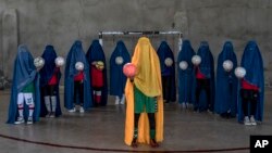 شماری از زنان و دختران معترض که با پوشیدن چادری توپ‌های فوتبال را به رسم اعتراض از مقررات سختگیرانهٔ طالبان به دست گرفته اند. 