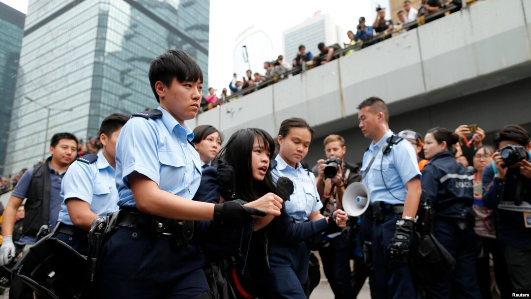 Seorang pengunjuk rasa diseret keluar dari lokasi protes oleh pihak berwenang Hong Kong (11/12). Lokasi di luar gedung pemerintah Hong Kong ini biasanya digunakan sebagai kamp utama para pemrotes pro-Demokrasi.