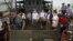 FILE - Myanmar government officials and U.N. officials stand on a boat used for human trafficking at a jetty outside Sittwe, Myanmar.