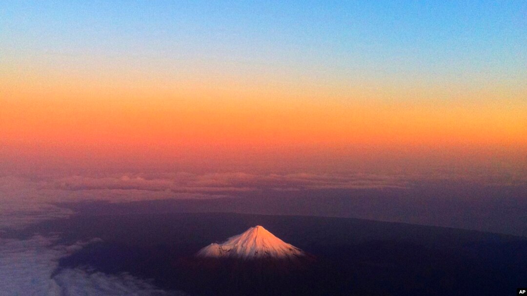 FILE - New Zealand's Taranaki Maunga, previously known as Mount Taranaki, has a warm glow lighting the snow peak, June 12, 2011.