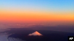 FILE - New Zealand's Taranaki Maunga, antecedently  known arsenic  Mount Taranaki, has a lukewarm  glow lighting the snowfall  peak, June 12, 2011.