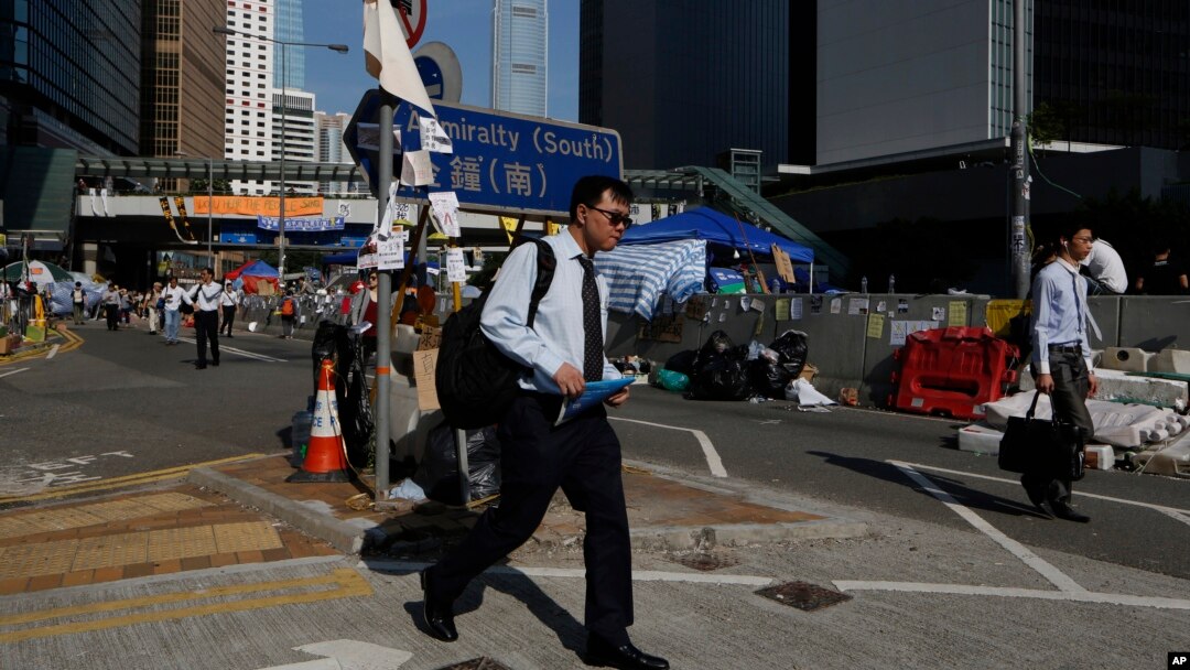 Pekerja menuju kantor di jalan utama tempat demonstrasi terjadi di Hong Kong (6/10). (AP/Kin Cheung)