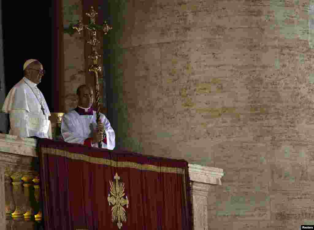Newly elected Pope Francis (L) appears on the balcony of St. Peter's Basilica after being elected by the conclave of cardinals, at the Vatican, March 13, 2013. Pope Francis, the former Cardinal Jorge Bergoglio of Argentina, delivered his first blessing to