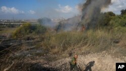 Një polic inspekton zonën përreth zjarrit në një zonë në pjesën qendrore të Izraelit, që u godit nga raketa e rebelëve huthi e hedhur nga Jemeni më 15 shtator, 2024/AP