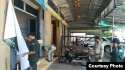 Police take down a banner outside an Adhoc office in Koh Kong province, Cambodia, Tuesday May 2, 2017. (Courtesty of Adhoc)