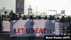 Orang-orang memegang spanduk sebelum berbaris di jalan selama protes di Kabul pada 21 Desember 2021, saat negara itu berjuang dengan krisis ekonomi yang mendalam. (Foto: AFP/Mohd Rasfan)