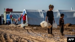 Syrian children carry jugs to fill with water in Washukanni camp, on Dec. 16, 2019, which was recently established on the outskirts of Hasakeh city for people displaced from the northeastern Syrian town of Ras Al Ain.