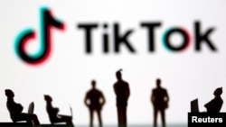 ARCHIVO - En esta imagen ilustrativa tomada el 15 de marzo de 2021 se ven pequeñas figuras de juguete frente al logotipo de TikTok.