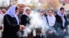 FILE - A woman burns incense during a mass funeral for Yazidi victims of the Islamic State group in the northern Iraqi village of Kojo in Sinjar district, Feb. 6, 2021.